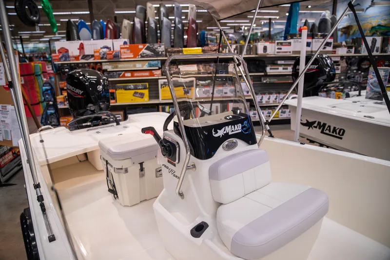 Slide: The Image of 2027 Mako Pro Skiff 17 CC boat displayed in a showroom with boating accessories. - 10
