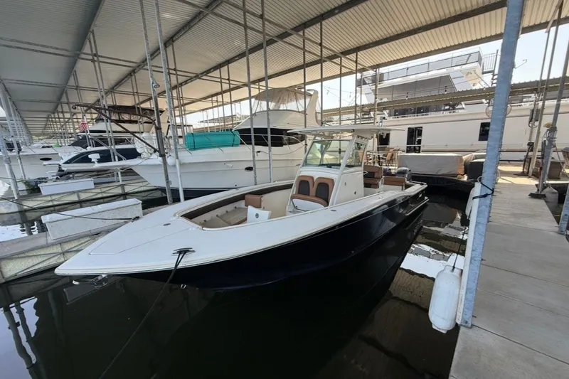 Slide: The Image of 2014 Scout 275 LXF boat docked in a marina under a covered shelter. - 4
