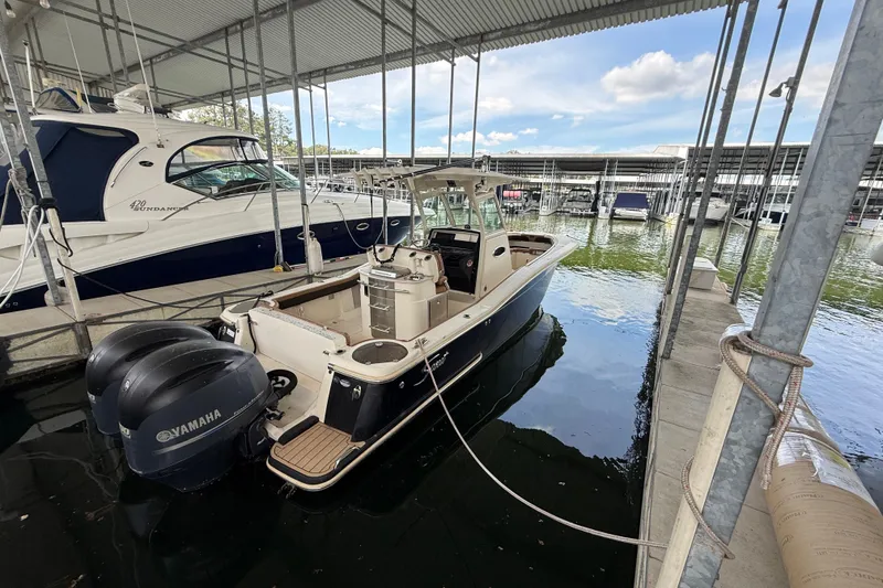 Slide: The Image of 2014 Scout 275 LXF boat docked with twin Yamaha engines in a marina. - 15