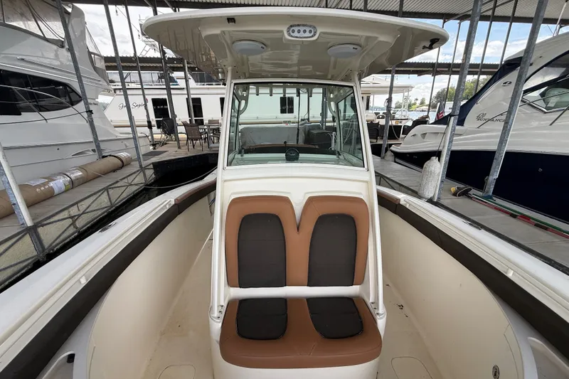 Slide: The Image of 2014 Scout 275 LXF boat interior with brown seating, docked in a marina. - 6
