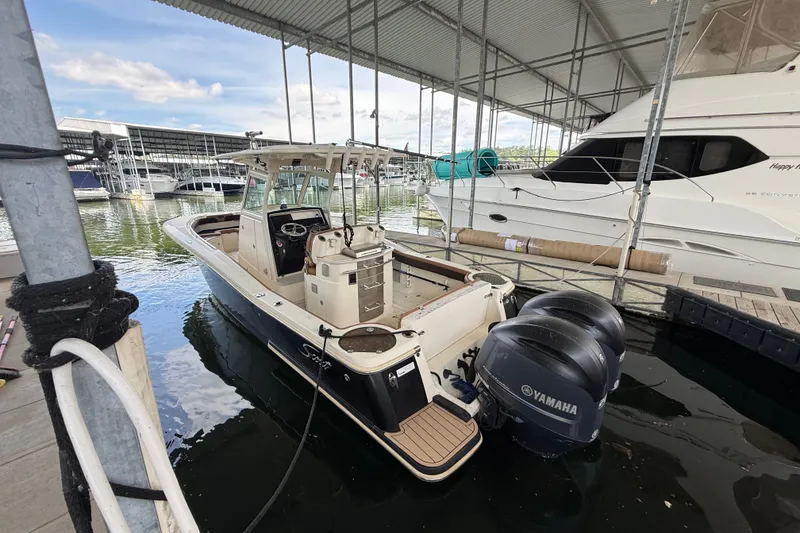 Slide: The Image of 2014 Scout 275 LXF boat docked with twin Yamaha engines in a marina. - 13