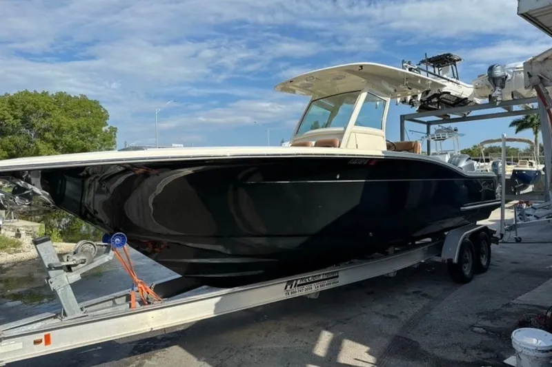 The Image of 2014 Scout 275 LXF boat on trailer, parked outdoors under blue sky. - 0