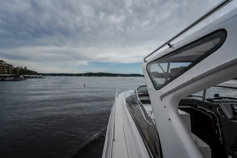 Slide: The Image of 2009 Regal Commodore 4460 yacht cruising on a serene lake under a cloudy sky. - 34