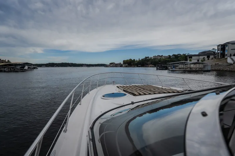Slide: The Image of 2009 Regal Commodore 4460 yacht cruising on a serene lake under a cloudy sky. - 29