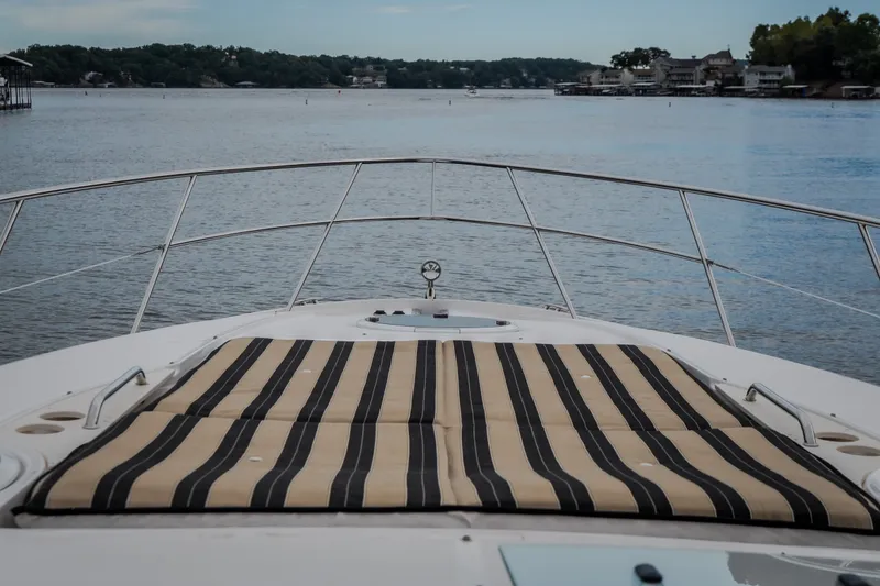 Slide: The Image of 2009 Regal Commodore 4460 yacht with striped deck cushions, overlooking serene lake view. - 28