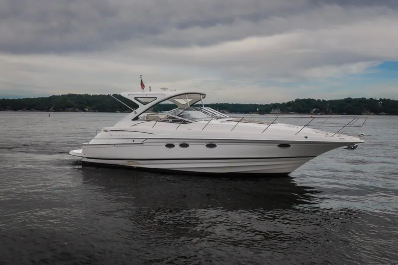 The Image of 2009 Regal Commodore 4460 yacht cruising on a calm lake under cloudy skies. - 2