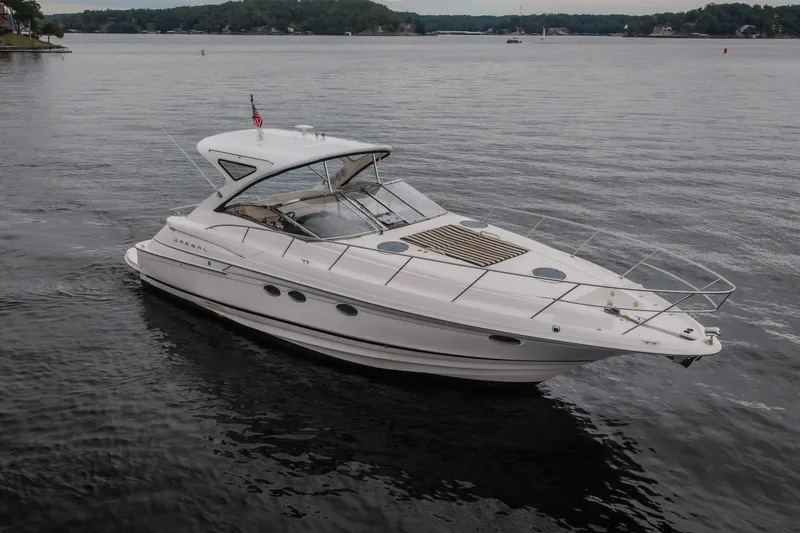 Slide: The Image of 2009 Regal Commodore 4460 yacht cruising on a serene lake with lush green shoreline. - 3