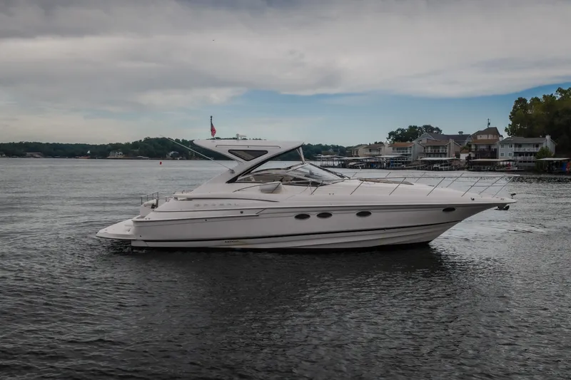 Slide: The Image of 2009 Regal Commodore 4460 yacht on a serene lake with waterfront homes. - 64