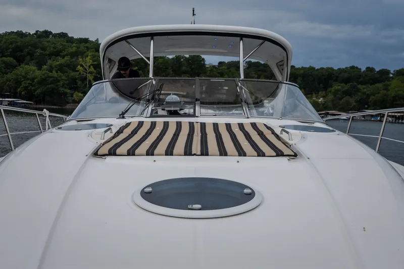 Slide: The Image of 2009 Regal Commodore 4460 yacht with striped deck cushion, docked by lush greenery. - 33
