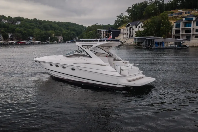 Slide: The Image of 2009 Regal Commodore 4460 yacht cruising on a scenic lake near waterfront homes. - 62
