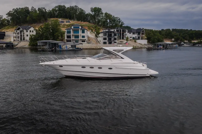 Slide: The Image of 2009 Regal Commodore 4460 yacht cruising on a scenic lake near modern waterfront homes. - 61