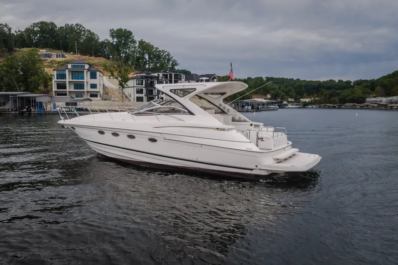 Slide: The Image of 2009 Regal Commodore 4460 yacht cruising on a scenic lake with modern homes in the background. - 66