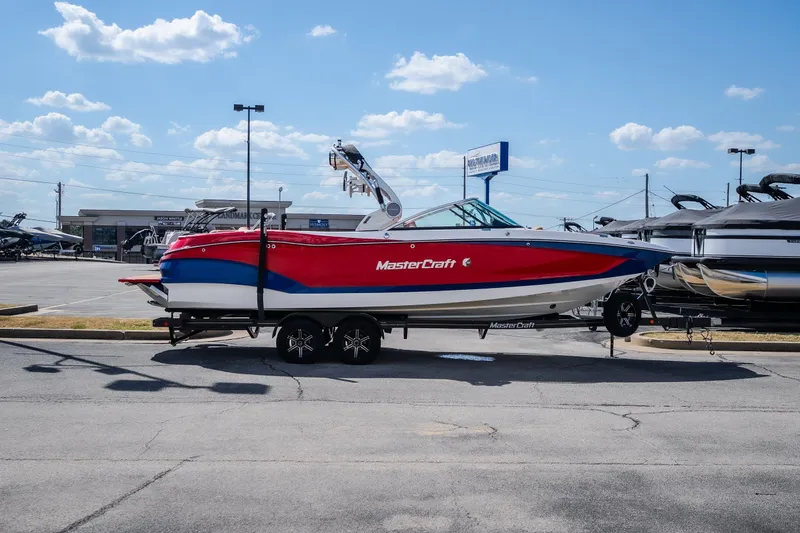 Slide: The Image of 2020 MasterCraft X26 boat on trailer in dealership lot under blue sky. - 6