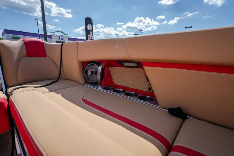 Slide: The Image of 2020 MasterCraft X26 boat interior with tan and red seating, cup holders, and speaker. - 45