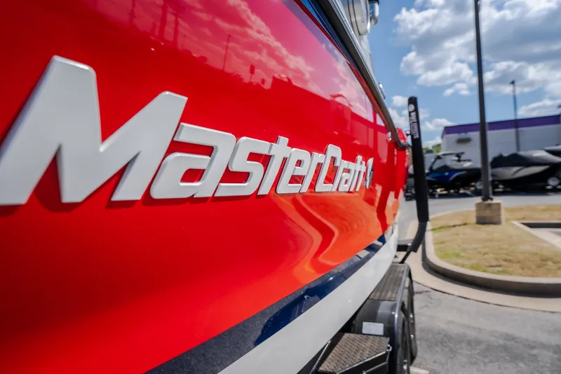 Slide: The Image of Red 2020 MasterCraft X26 boat with logo, parked outdoors under a blue sky. - 4