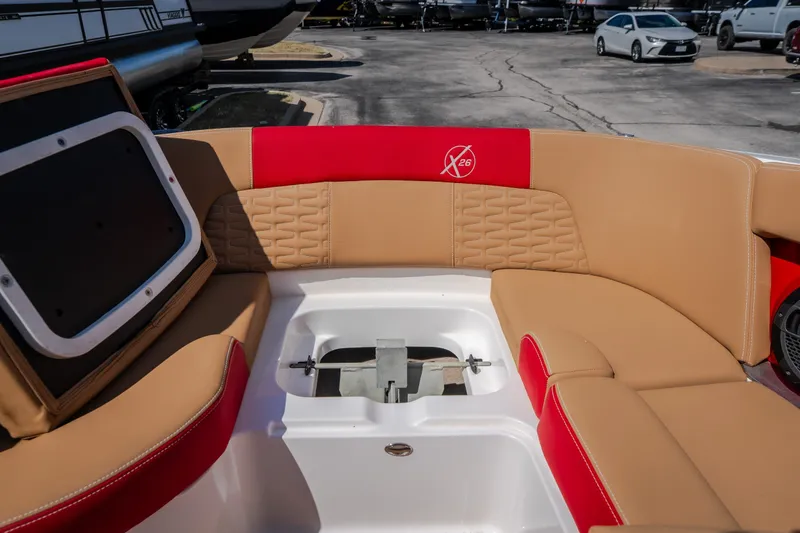 Slide: The Image of 2020 MasterCraft X26 boat interior with tan and red seating, docked in a marina. - 23