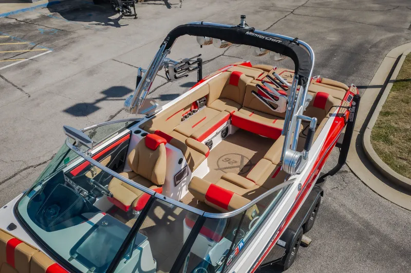 Slide: The Image of 2020 MasterCraft X26 boat with red and beige interior, parked on pavement. - 62