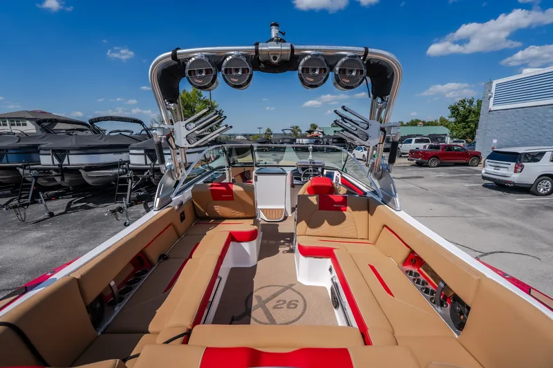 Slide: The Image of 2020 MasterCraft X26 boat interior with tan and red seating, docked under a clear blue sky. - 19