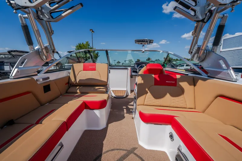 Slide: The Image of 2020 MasterCraft X26 boat interior with tan and red seating under a clear blue sky. - 47