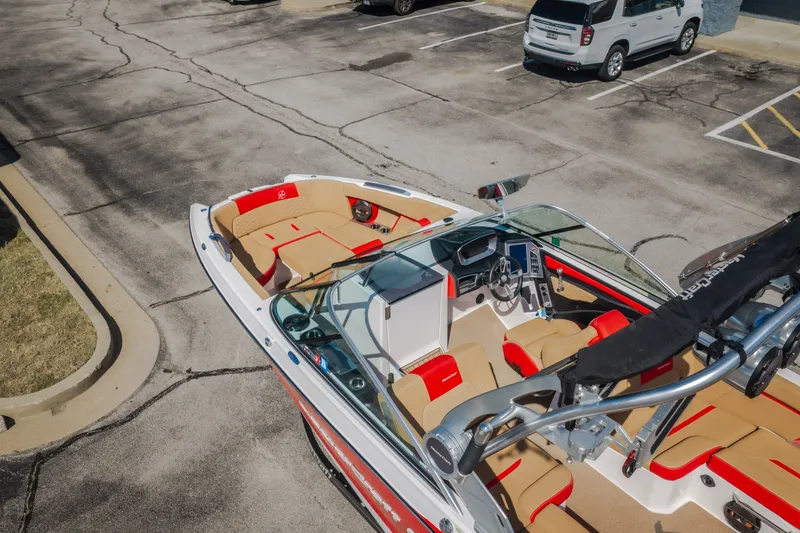 Slide: The Image of 2020 MasterCraft X26 boat with tan and red interior, parked in a lot. - 64