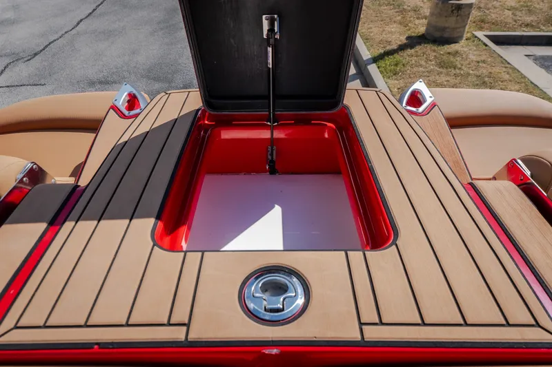 Slide: The Image of 2020 MasterCraft X26 boat storage compartment with open lid, featuring sleek wood finish. - 53