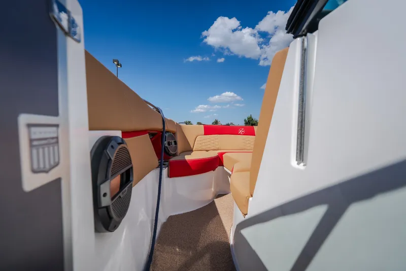 Slide: The Image of 2020 MasterCraft X26 boat interior with tan and red seating under a clear blue sky. - 27