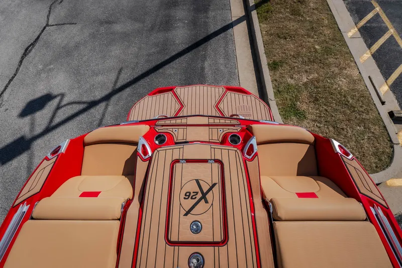 Slide: The Image of 2020 MasterCraft X26 boat with red and tan seating, parked on pavement. - 59