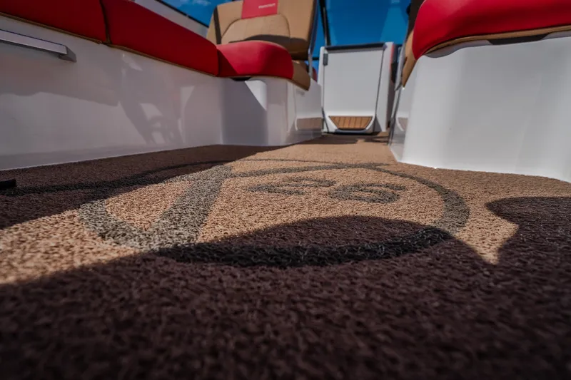 Slide: The Image of 2020 MasterCraft X26 boat interior with logo on carpet, featuring red and beige seating. - 48