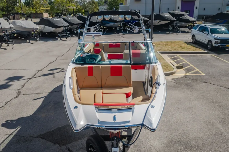 Slide: The Image of 2020 MasterCraft X26 boat with red and beige interior, parked in a dealership lot. - 61
