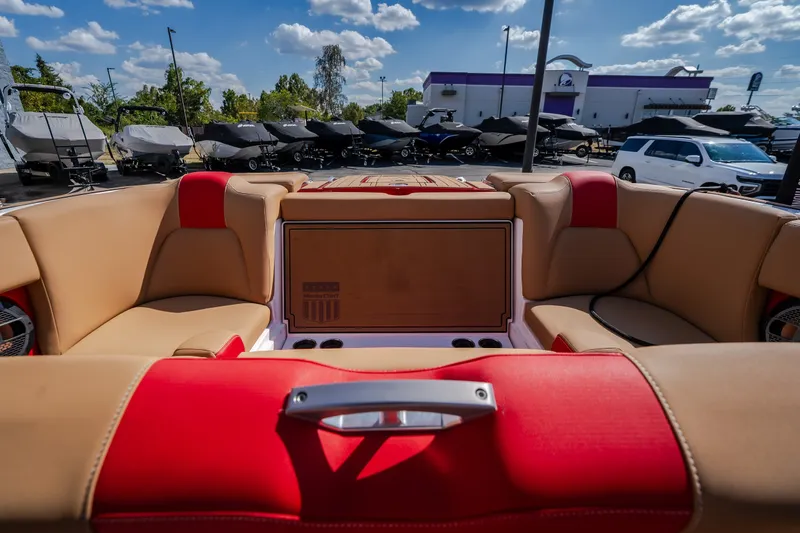 Slide: The Image of 2020 MasterCraft X26 boat interior with tan and red seating under a blue sky. - 50