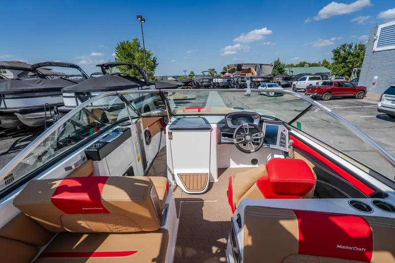 Slide: The Image of 2020 MasterCraft X26 boat interior with red and beige seating, parked outdoors. - 34