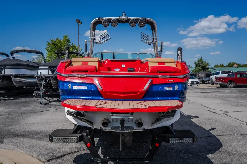 Slide: The Image of 2020 MasterCraft X26 boat, red and blue, parked outdoors under a clear blue sky. - 7