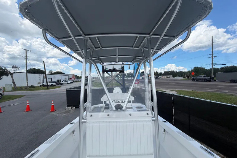Slide: The Image of 2021 Dusky 227 Open Fisherman boat with T-top, parked near a road under a cloudy sky. - 50