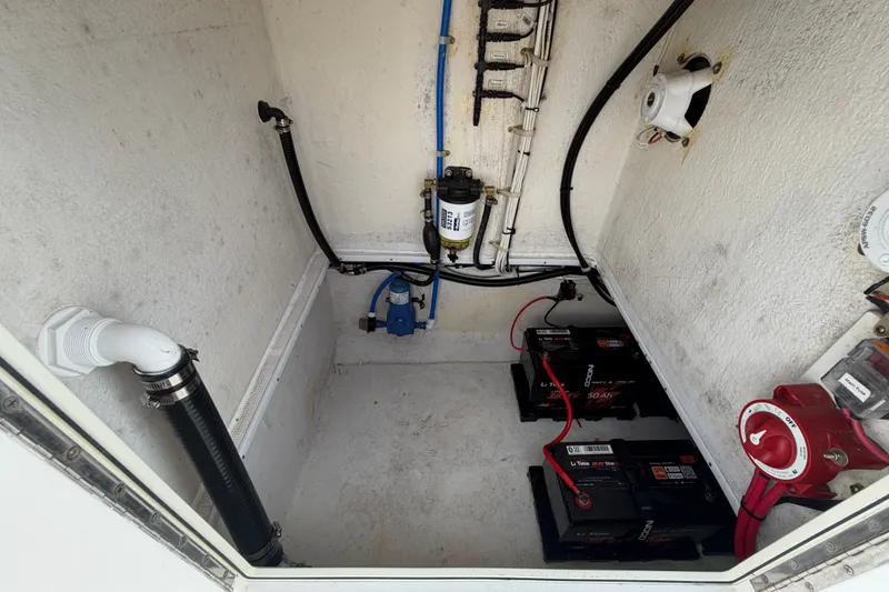 Slide: The Image of 2021 Dusky 227 Open Fisherman boat compartment with batteries, wiring, and plumbing components. - 54