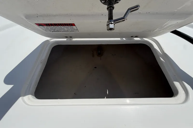 Slide: The Image of Open storage compartment on 2021 Dusky 227 Open Fisherman boat, featuring a warning label. - 38