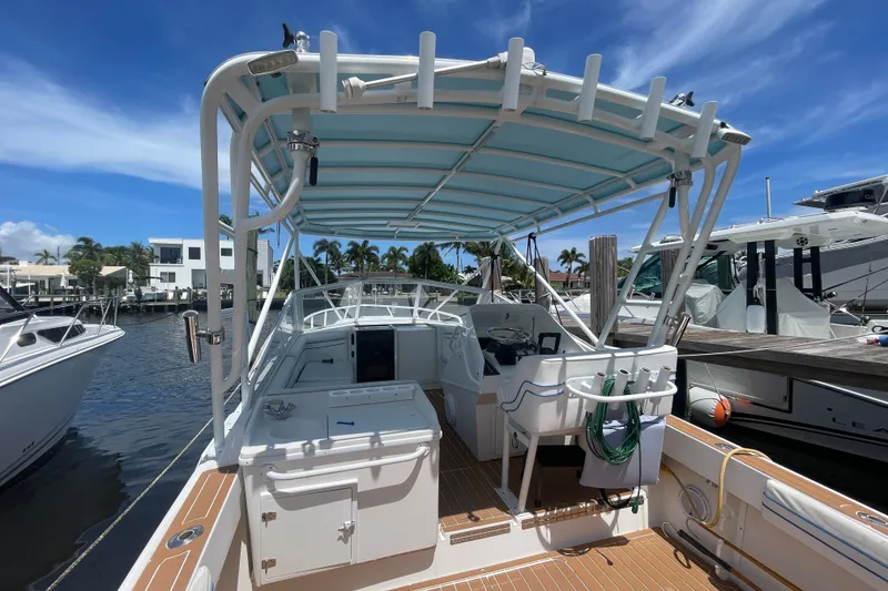 Slide: The Image of 2007 Contender 35 Side Console boat docked, featuring spacious deck and canopy under clear skies. - 7