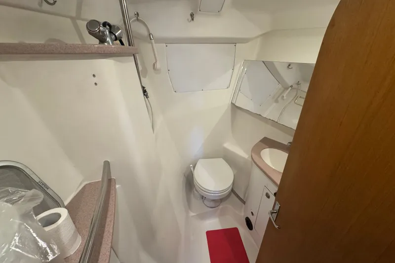 Slide: The Image of Compact bathroom in a 1999 Hunter 420 sailboat, featuring a toilet, sink, and shower. - 8
