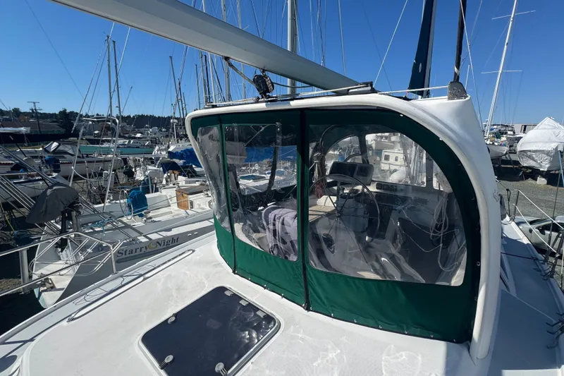 Slide: The Image of 1999 Hunter 420 sailboat with green cockpit cover, docked among other boats. - 30