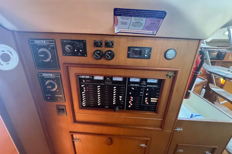Slide: The Image of Control panel of a 1999 Hunter 420 sailboat, featuring various switches and gauges. - 16