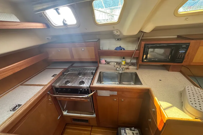 Slide: The Image of Interior of a 1999 Hunter 420 sailboat kitchen with stove, sink, and microwave. - 12