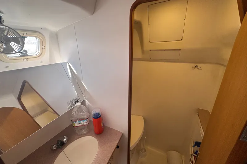 Slide: The Image of Compact bathroom in a 1999 Hunter 420 sailboat, featuring a sink, mirror, and ventilation. - 20