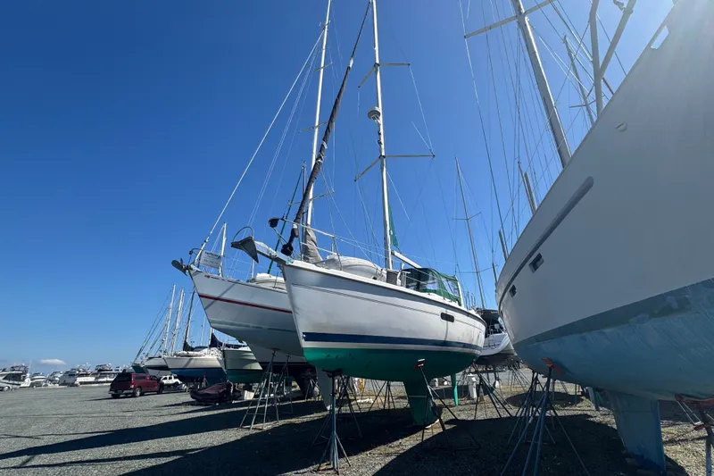 Slide: The Image of Sailboats, including a 1999 Hunter 420, docked on land under a clear blue sky. - 1