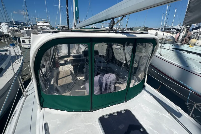 Slide: The Image of 1999 Hunter 420 sailboat with green cockpit enclosure, docked at marina. - 29