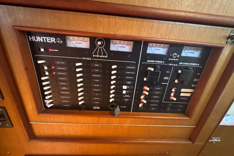 Slide: The Image of Control panel of a 1999 Hunter 420 sailboat with various switches and meters. - 17