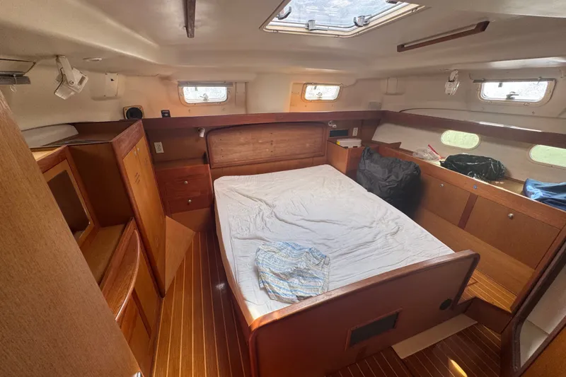 Slide: The Image of Interior of a 1999 Hunter 420 sailboat cabin with wooden furnishings and a bed. - 18