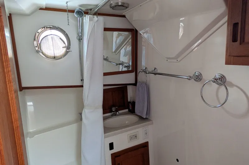 Slide: The Image of Bathroom interior of 2010 Nordic Tug 32 with porthole, sink, and shower curtain. - 42