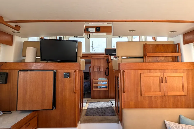 Slide: The Image of Interior of 2010 Nordic Tug 32, featuring wood cabinetry, seating, and a mounted TV. - 21