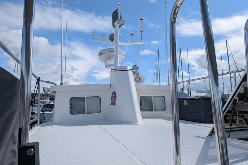 Slide: The Image of 2010 Nordic Tug 32 boat deck with radar and antennas, docked under a blue sky. - 11