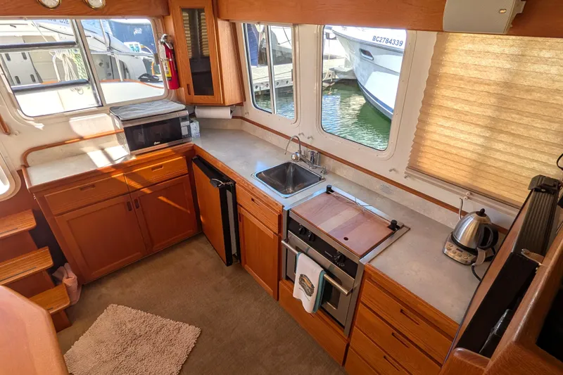Slide: The Image of Cozy kitchen interior of 2010 Nordic Tug 32 boat with wooden cabinetry and appliances. - 19