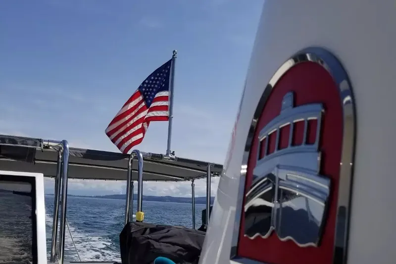 Slide: The Image of Nordic Tug 32 (2010) with American flag, cruising on open water under clear skies. - 1
